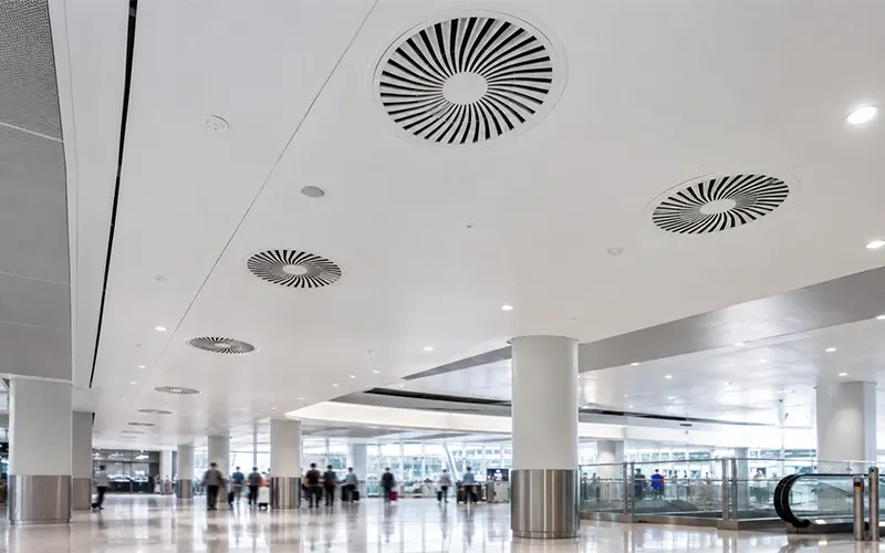 Modernes Flughafenterminal mit HLK-Luftauslässen an der Decke zur Unterstützung der Luftfiltration und Luftqualität in öffentlichen Passagierbereichen.